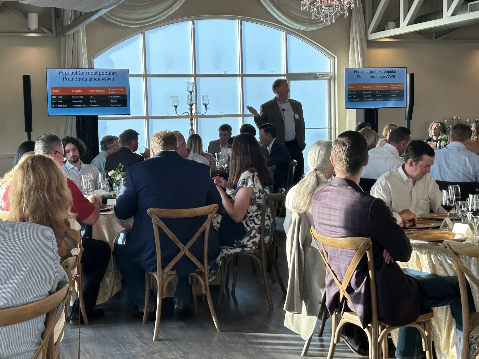Truss-mounted display showing a presentation to seated guests