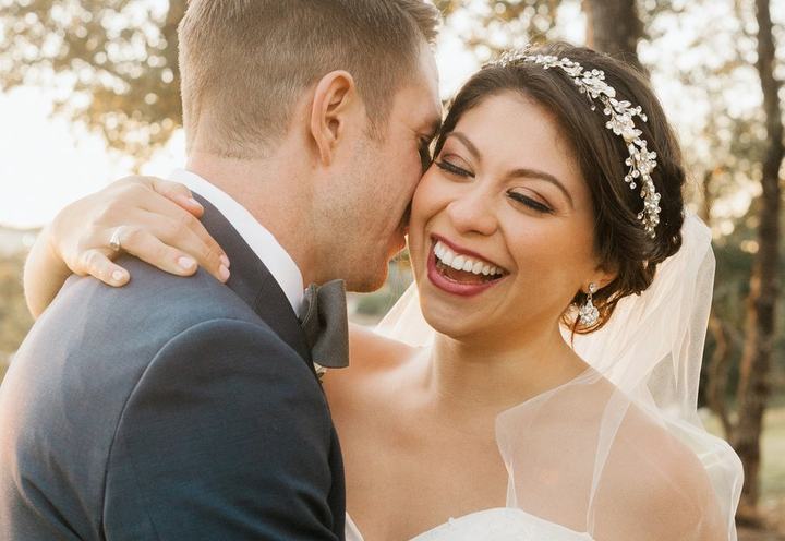 Laughing bride with an updo and crystal headpiece, hair and makeup by All Dolled Up
