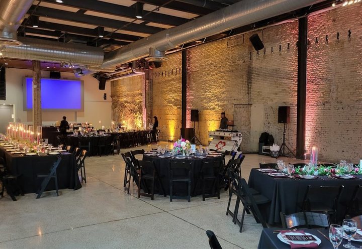 Banquet room at 800 Congress with draped tables and a projector screen along the brick wall