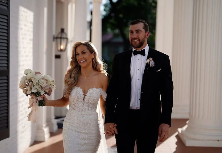 Bride and groom walking between white columns, by Cloud Craft Studios