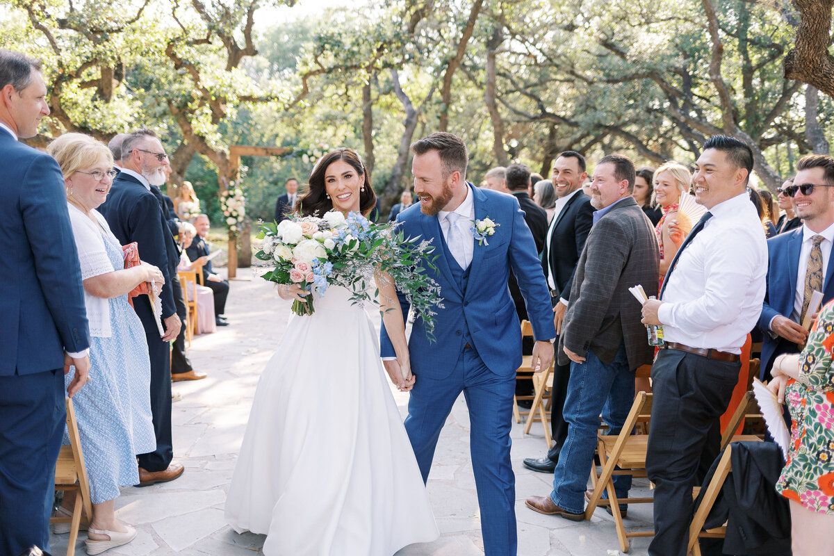 Couple walking back up the aisle under live oaks
