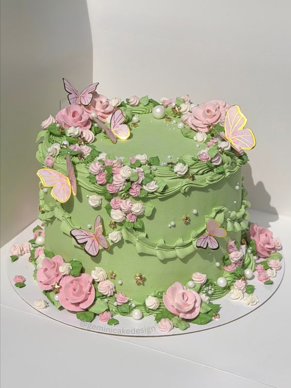 Green garden cake with pink piped roses and butterflies