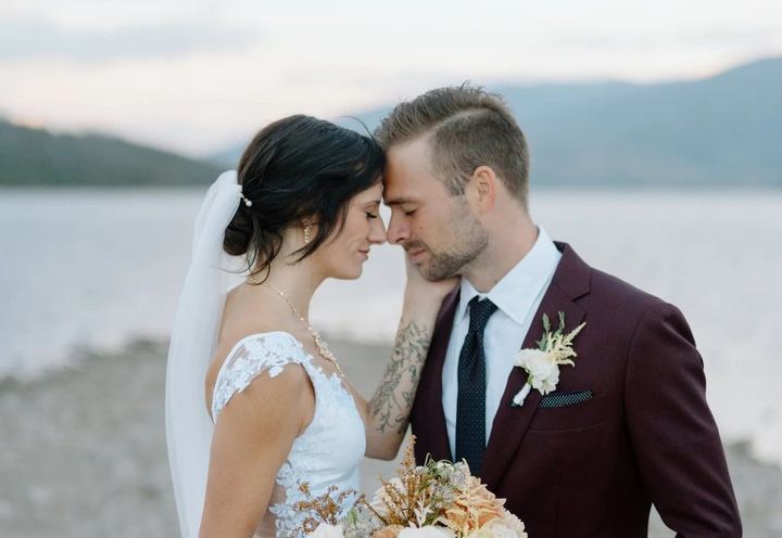 Bride and groom forehead to forehead by a lake, from Kelton Film Co.