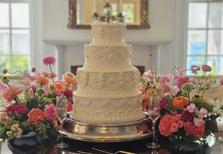 Tiered wedding cake surrounded by flowers by Michelle's Patisserie