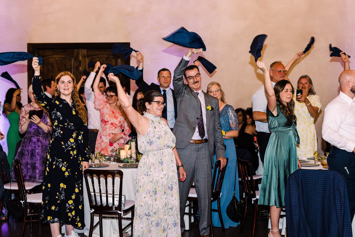 Guests on their feet waving navy napkins over their heads for the grand entrance in the Ma Maison main hall