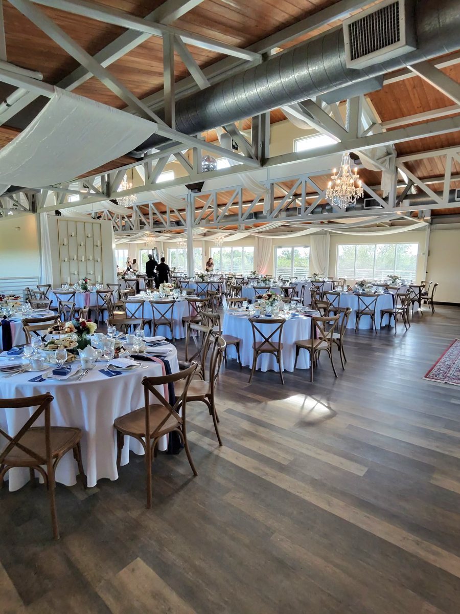 The hall at The Terrace Club set with round tables under the white beams