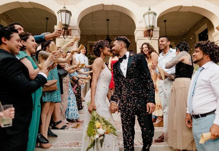 Newlyweds walking through cheering guests and confetti, from Satin Wedding Co.