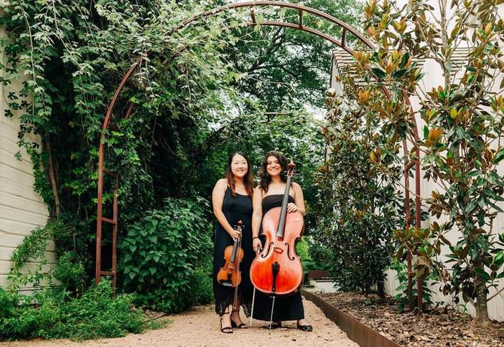 Two Sienna String Quartet players with violin and cello in a garden