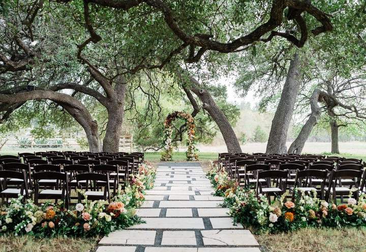 Ceremony aisle under oaks lined with flowers by Sixpence Floral Design