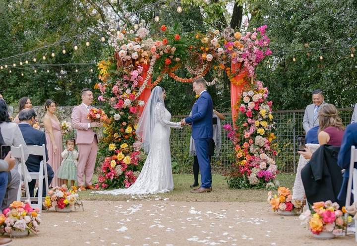 Ceremony at a colorful floral arch by Tiffany Larson Design Co.